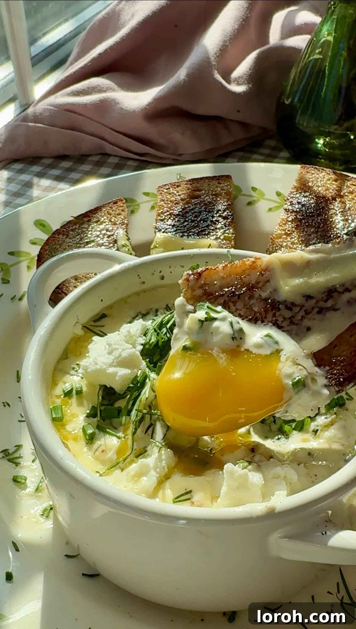 Dunking buttery toast into a ramekin of creamy Oeufs Cocotte (baked eggs) with feta and spinach.