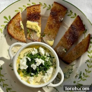 Baked eggs and feta in a ramekin on a plate with toast.