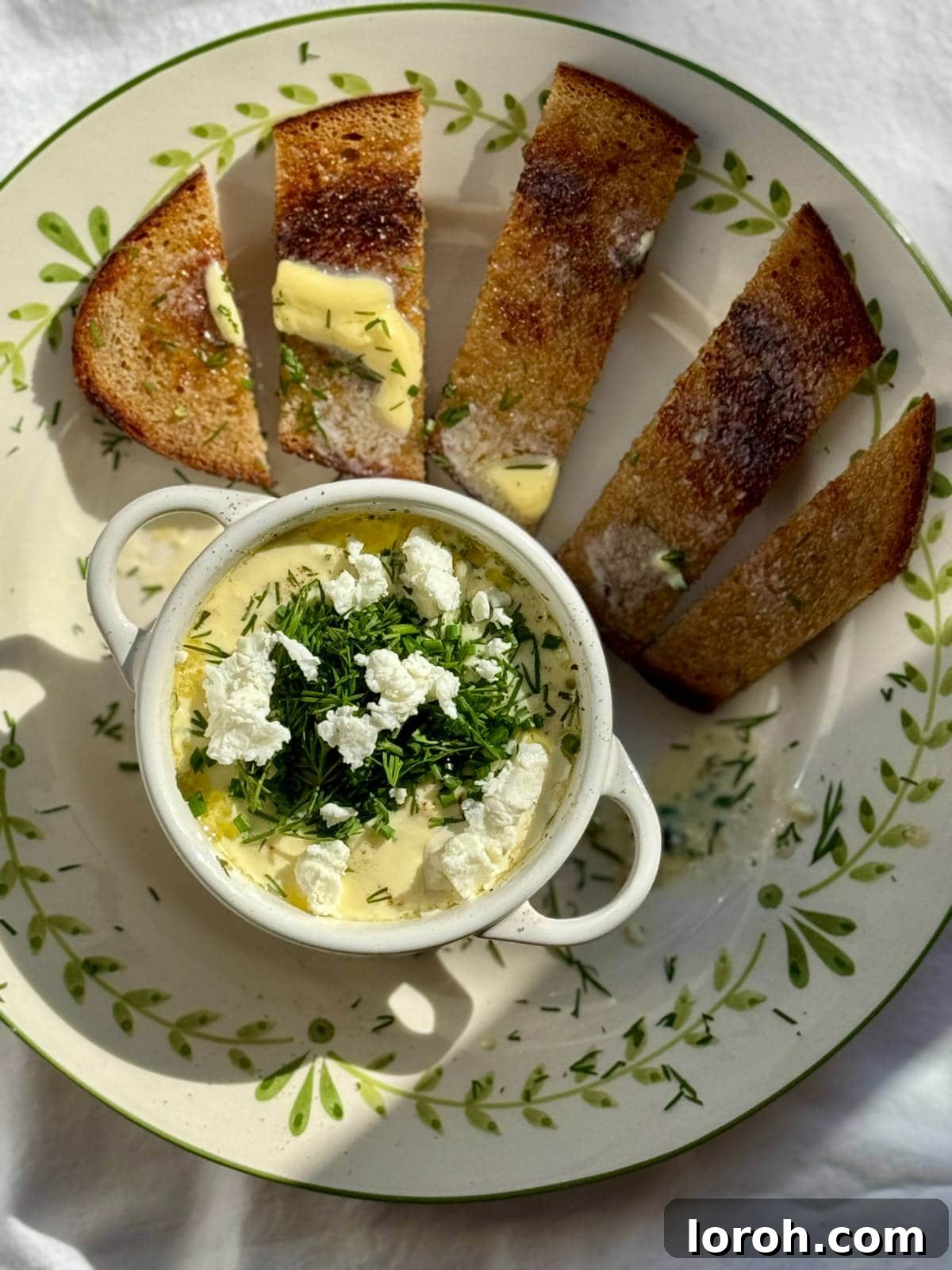 Two Oeufs Cocotte (baked eggs) on a plate, served with hot buttered toast, ready for dipping.