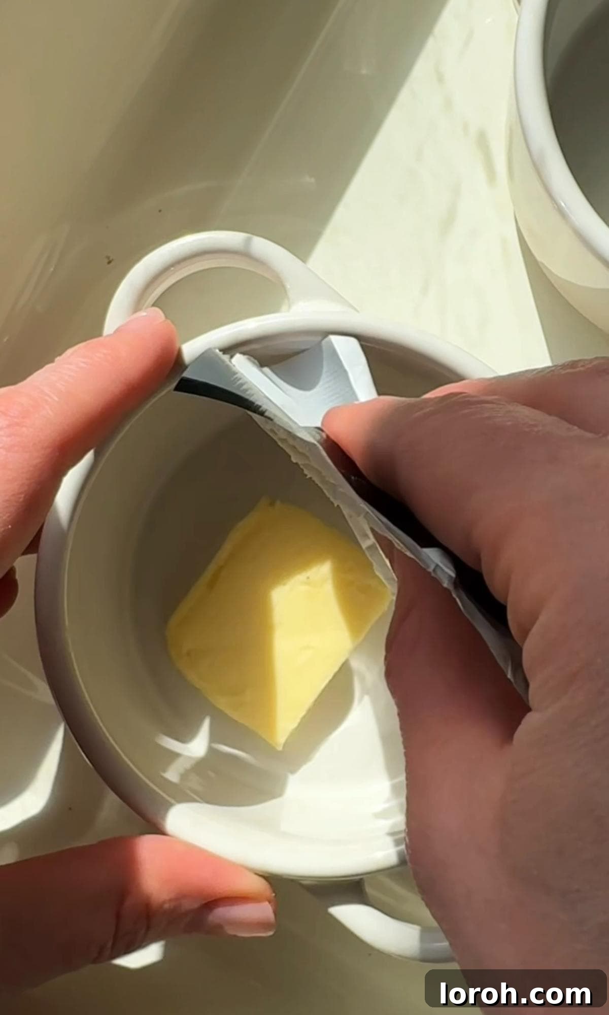 Butter being spread generously inside a ramekin before baking eggs.
