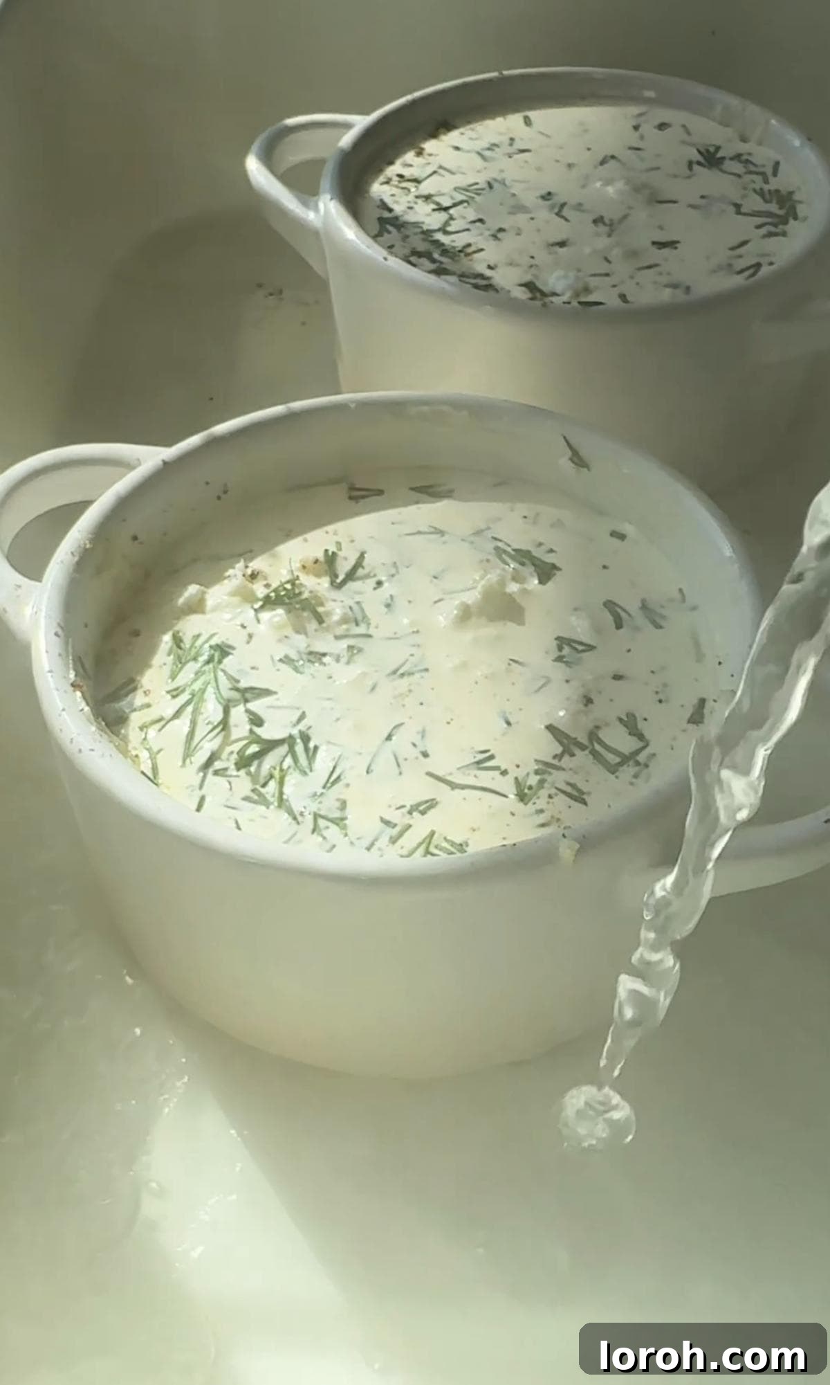 Ramekins with Oeufs Cocotte ingredients placed in a roasting tin with boiling water for a water bath.