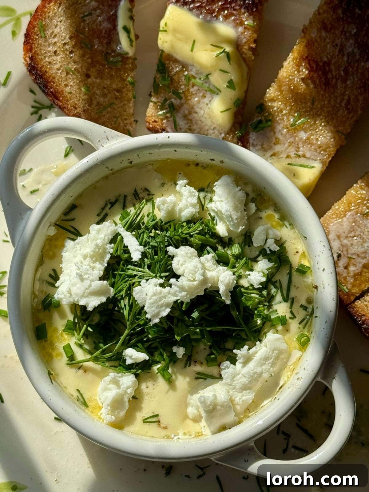 Close-up of a rustic Oeufs Cocotte served with golden, buttered toast, highlighting the creamy texture.
