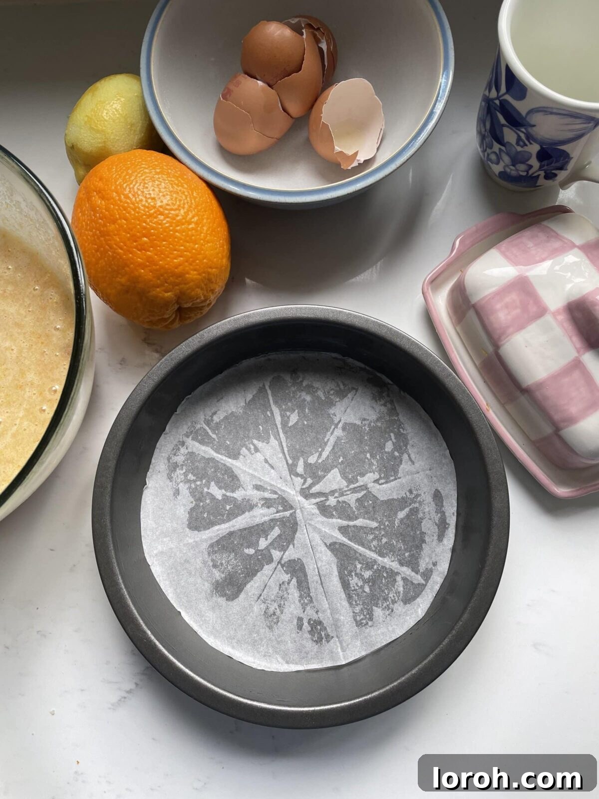 The process of meticulously lining a cake tin with baking parchment for the Tunisian Orange Cake.
