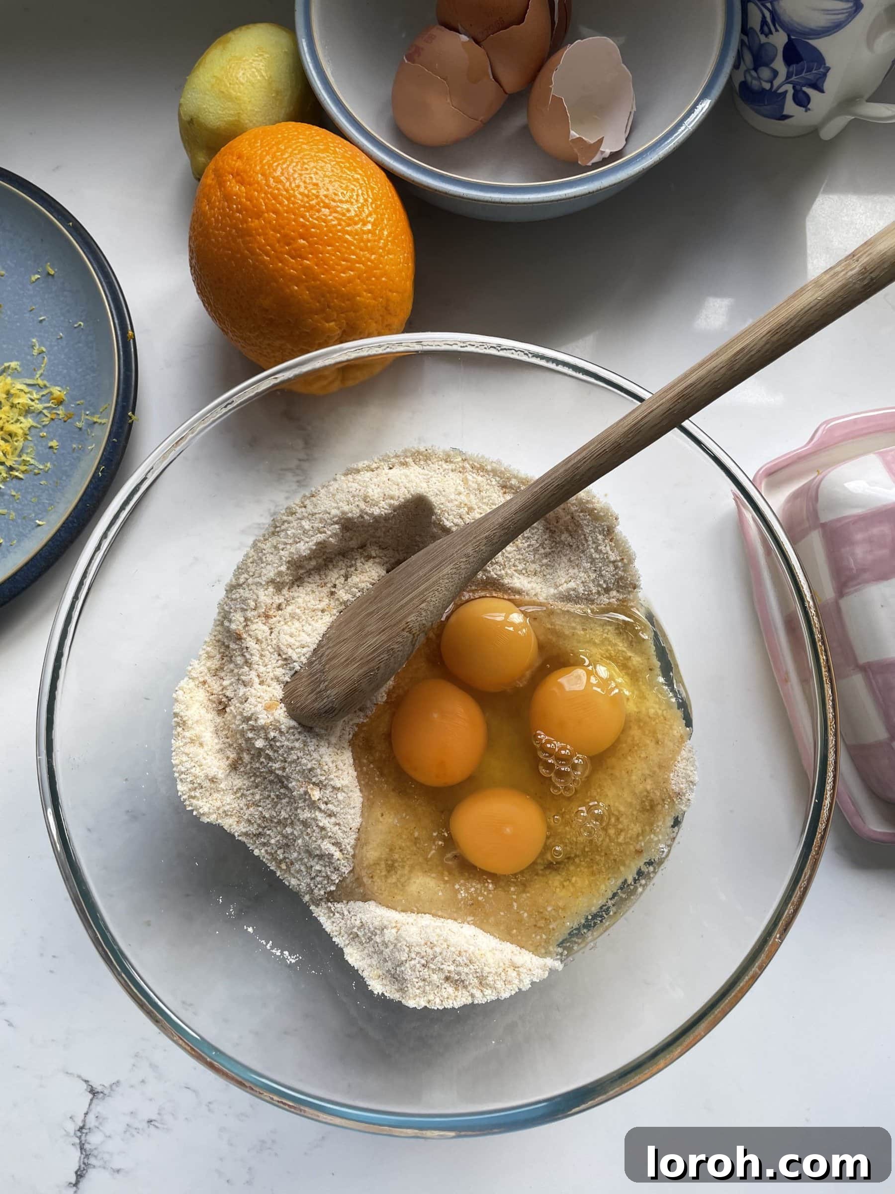 Adding farm-fresh eggs to the dry ingredients mixture in a glass mixing bowl.