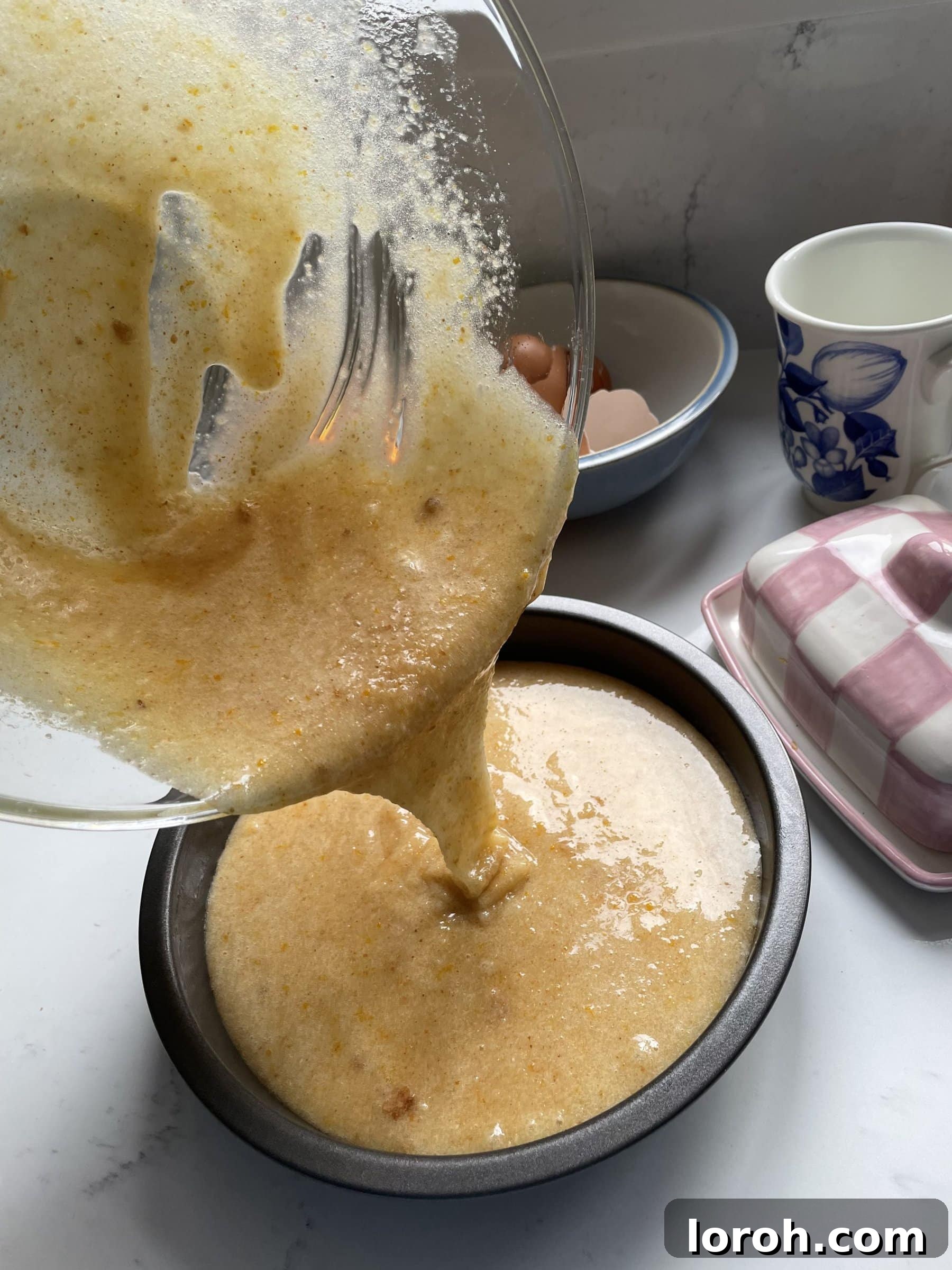 Pouring the Tunisian orange cake mix into the prepared lined cake tin.