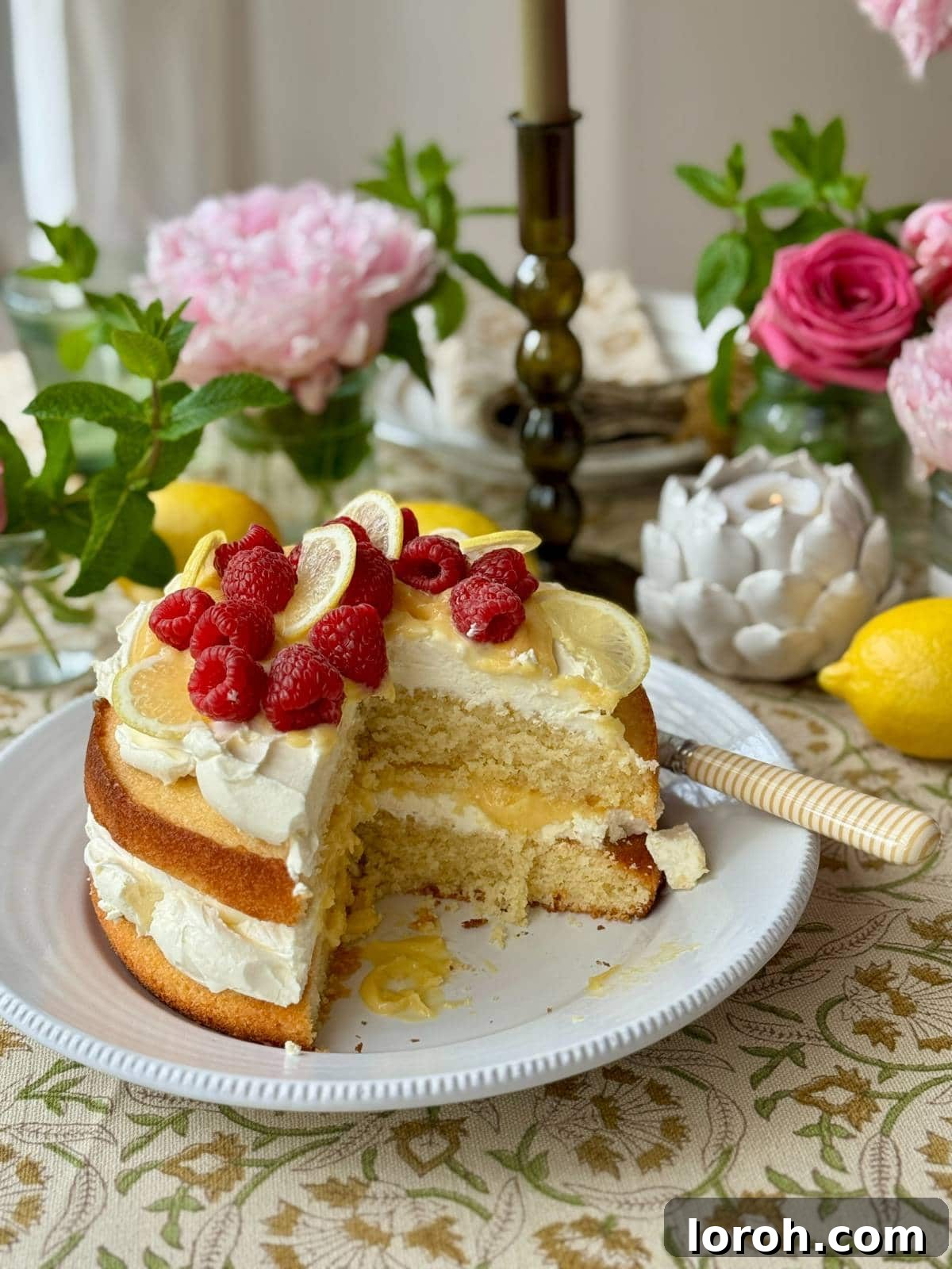 A slice of lemon curd cake removed, revealing its beautiful layers of zesty sponge, bright lemon curd, and creamy mascarpone filling.