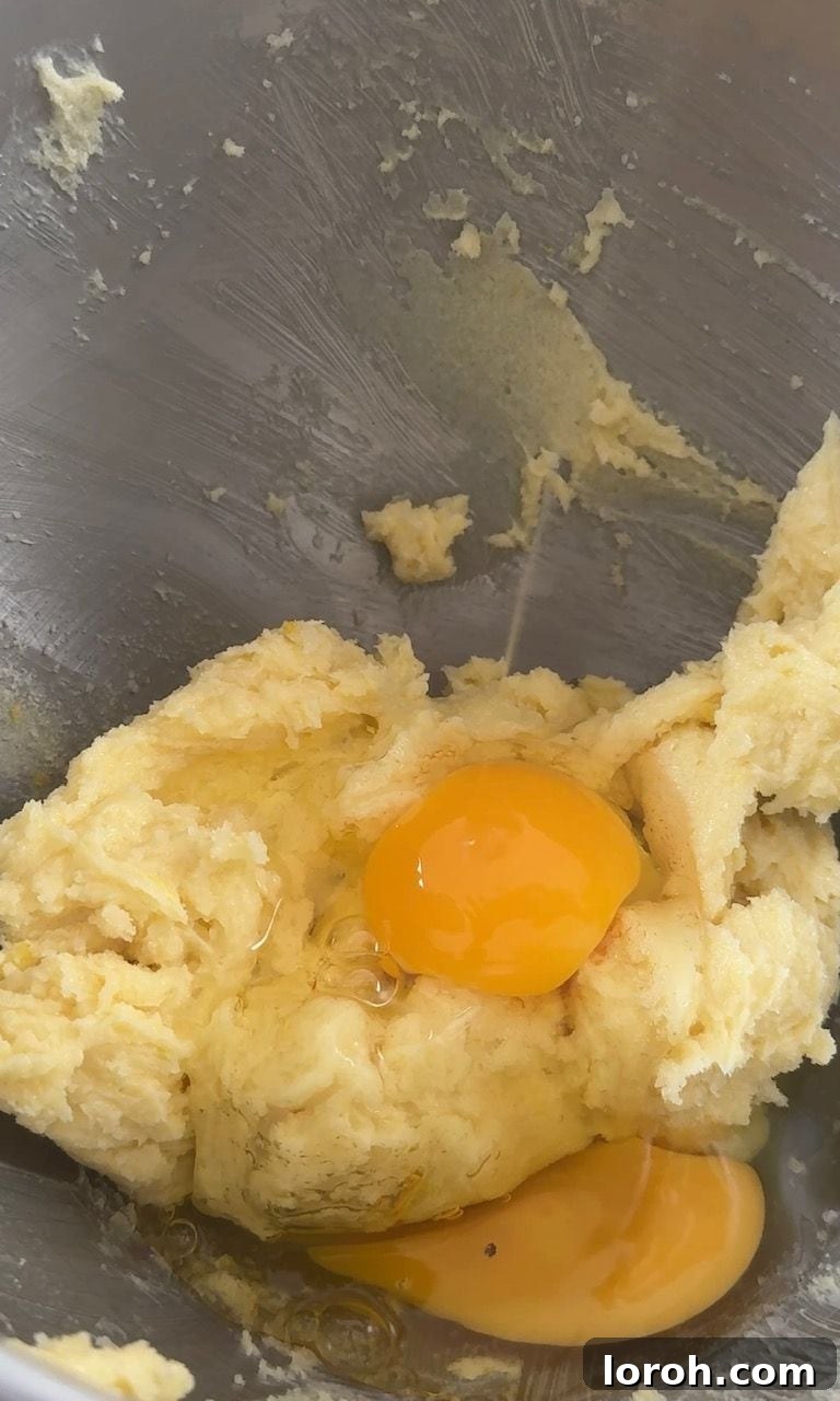 Cracked eggs being added to the creamed butter and sugar mixture, ready for beating.