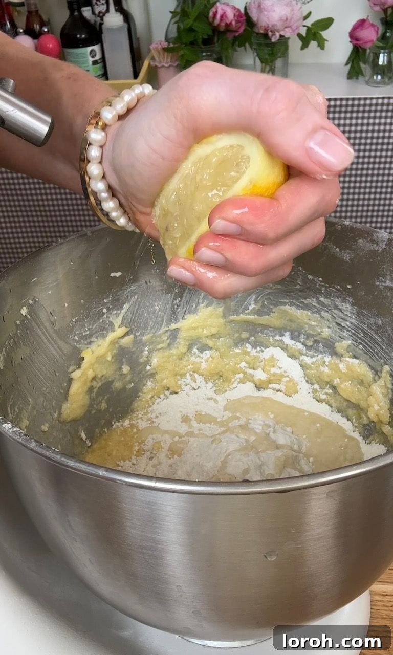 Fresh lemon juice being squeezed directly into the cake batter, adding a crucial liquid component.
