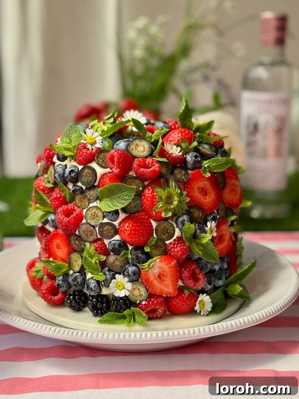 A beautifully decorated fresh berry cake on a white cake stand, ready to be served.