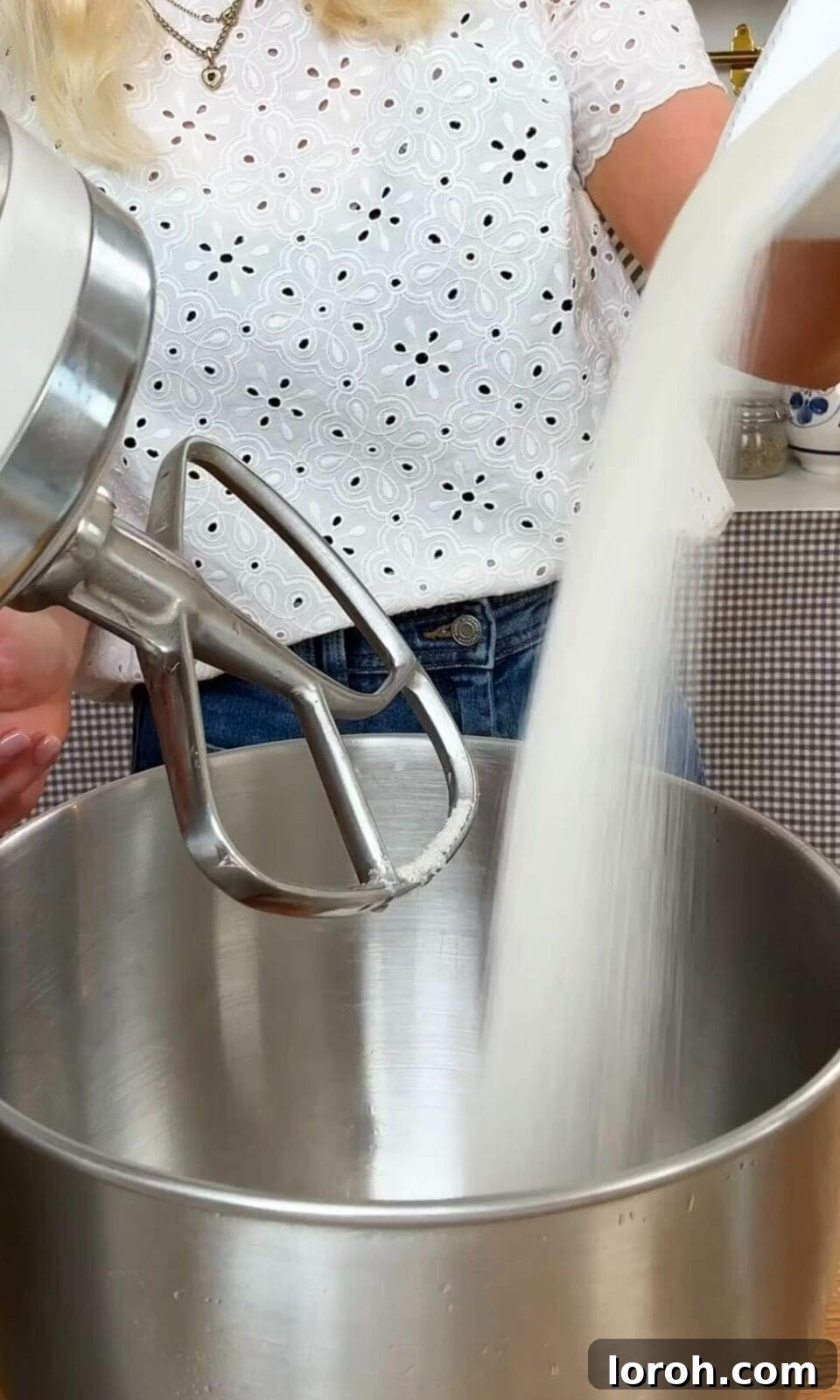 Adding caster sugar to a bowl with eggs in a stand mixer.