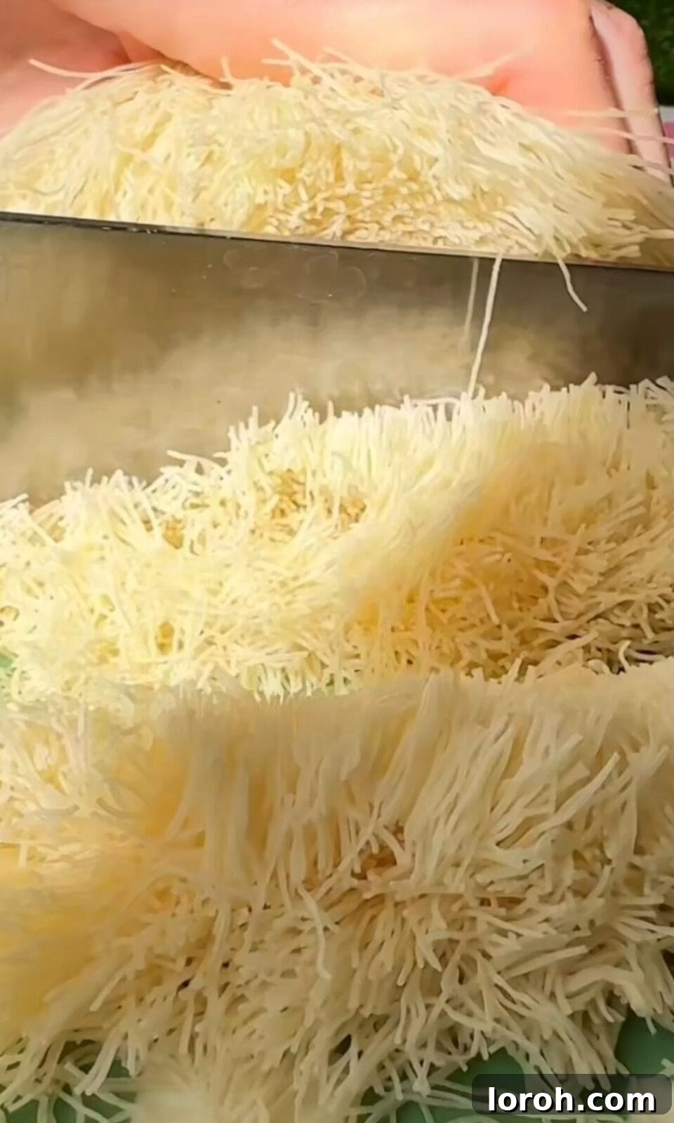 Slicing kataifi pastry into smaller pieces for toasting.