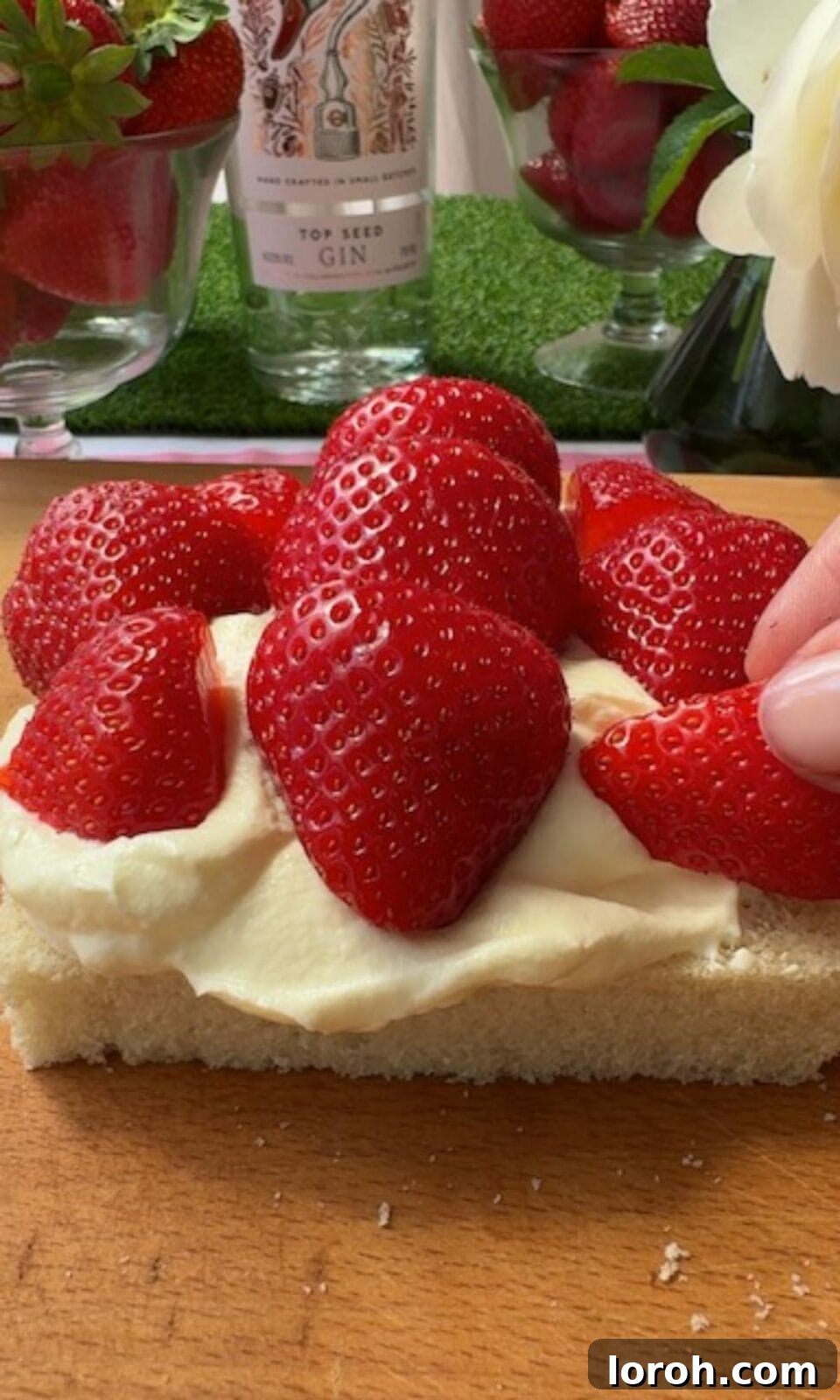 Carefully arranging whole strawberries in a pattern on whipped cream for a Japanese fruit sandwich.