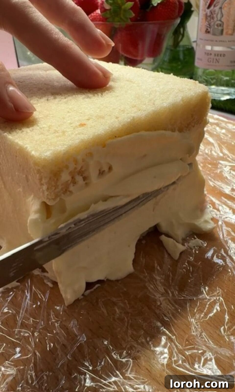 Adding and smoothing the final layer of whipped cream over strawberries and bread for a Japanese sando.
