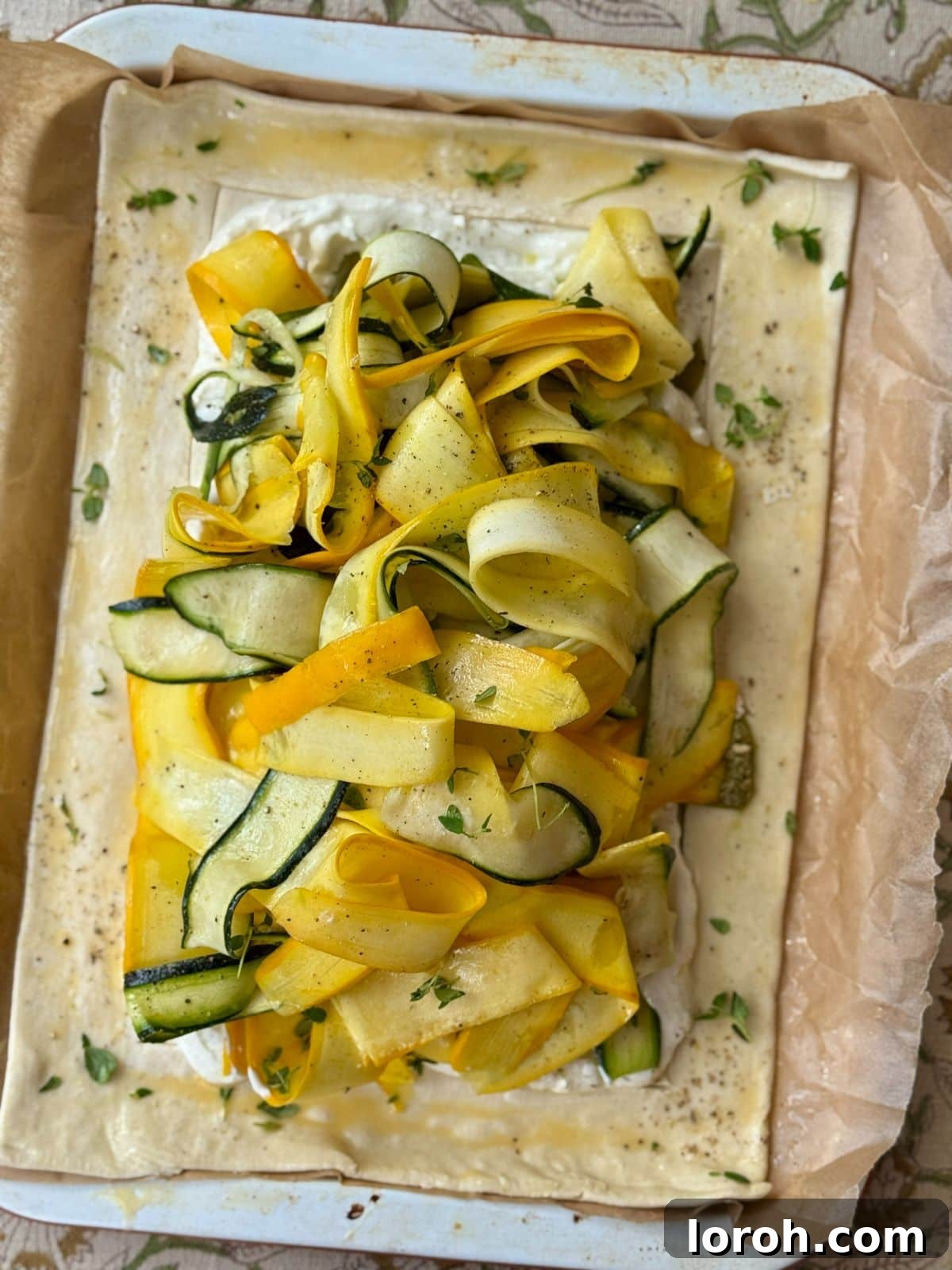 Golden Zucchini Tart 4 Close-up of a courgette tart pre-baking, showing the scored puff pastry edge and the creamy filling with courgette ribbons.