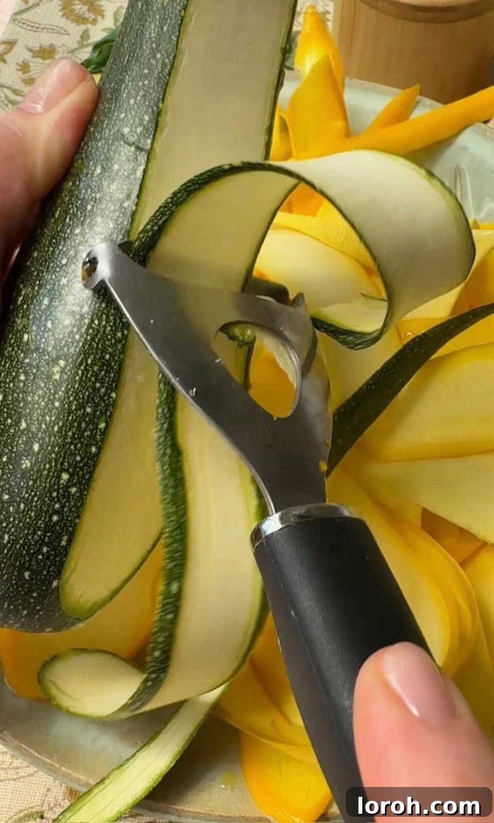 Golden Zucchini Tart 5 A hand using a vegetable peeler to create thin ribbons of fresh green courgette.