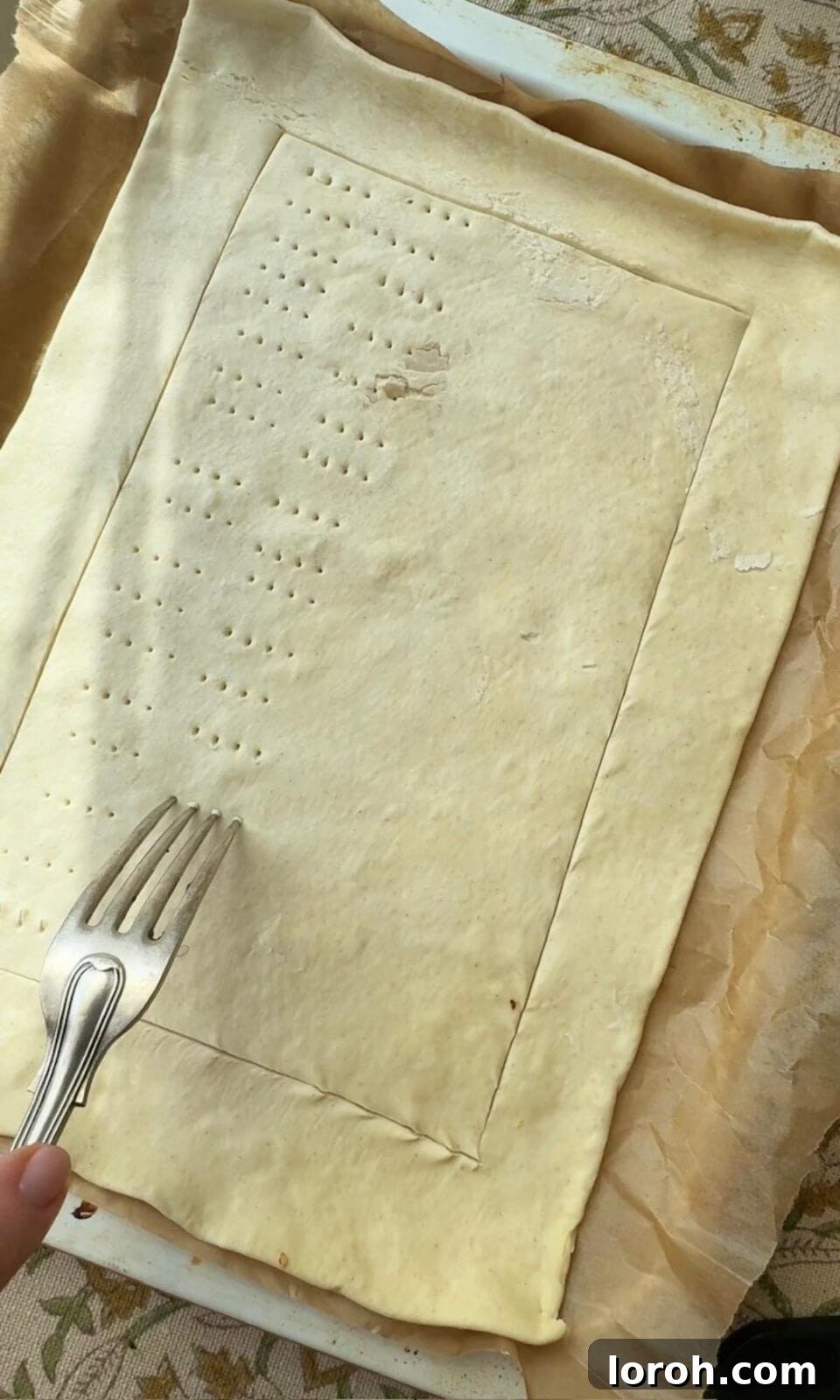 Golden Zucchini Tart 7 Puff pastry laid out on parchment paper on a baking tray, with a border scored and the center pricked with a fork.