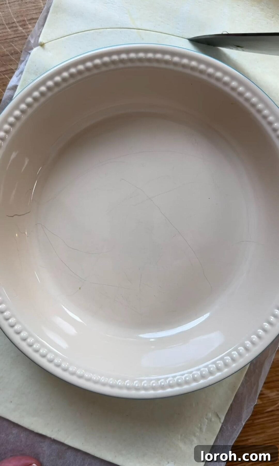 Cutting out puff pastry into a circle slightly larger than the tart tin.