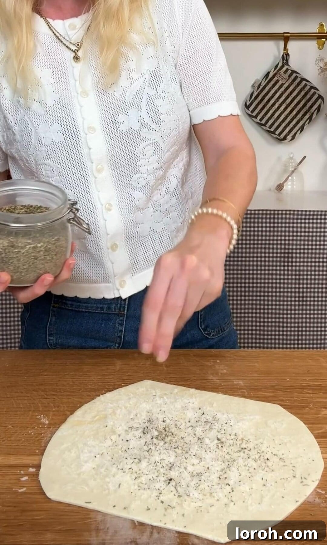 Garnishing the puff pastry with grated Parmesan cheese and mixed herbs before flipping.