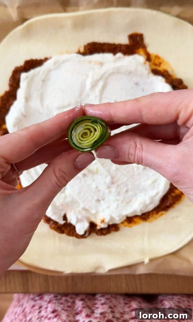 Golden Zucchini Feta Galette 7 A courgette ribbon being carefully curled into a tight spiral to form the center of the galette.