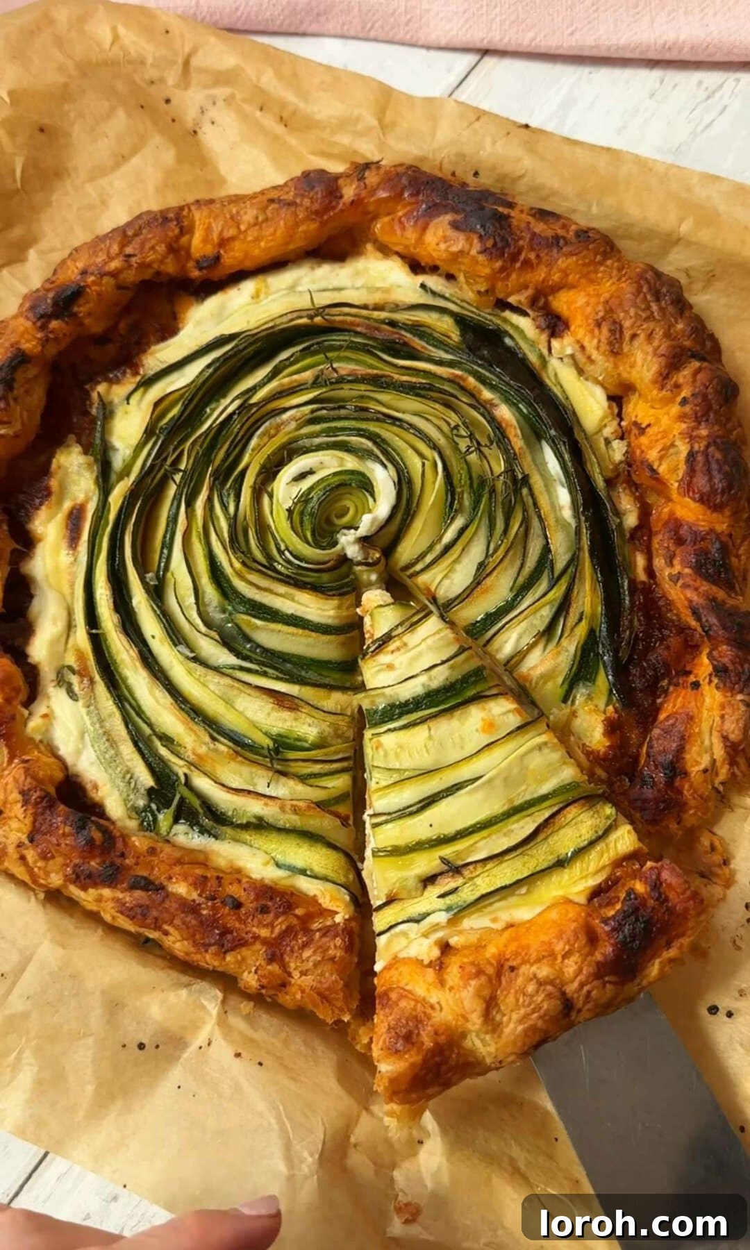 Golden Zucchini Feta Galette 9 A baked and sliced Galette de Courgettes on a wooden serving board, showing its golden crust and caramelized courgettes.