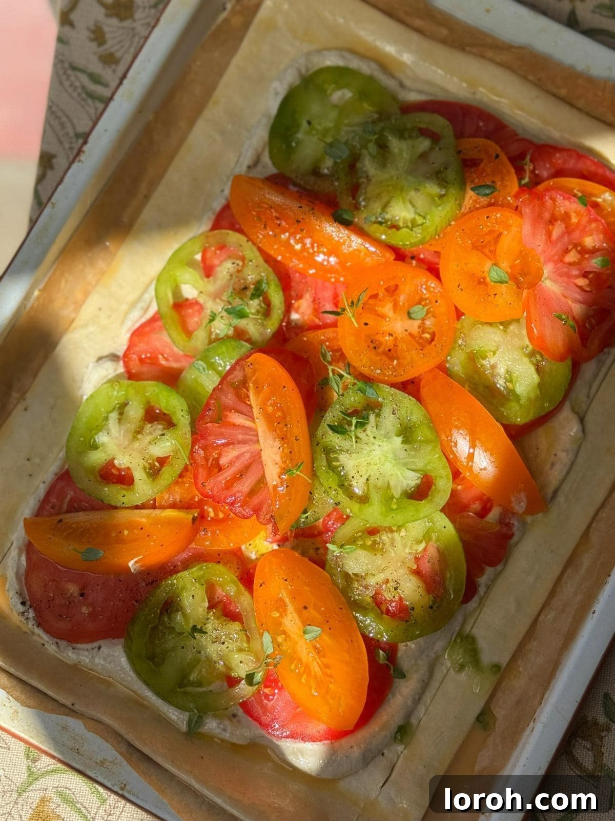 Vibrant heritage tomatoes, perfectly sliced and arranged on puff pastry, ready for baking.