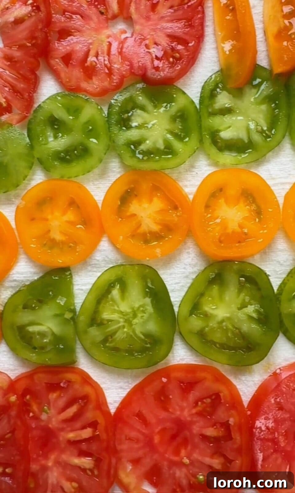 Sliced tomatoes being salted on a clean tea towel to draw out excess moisture.