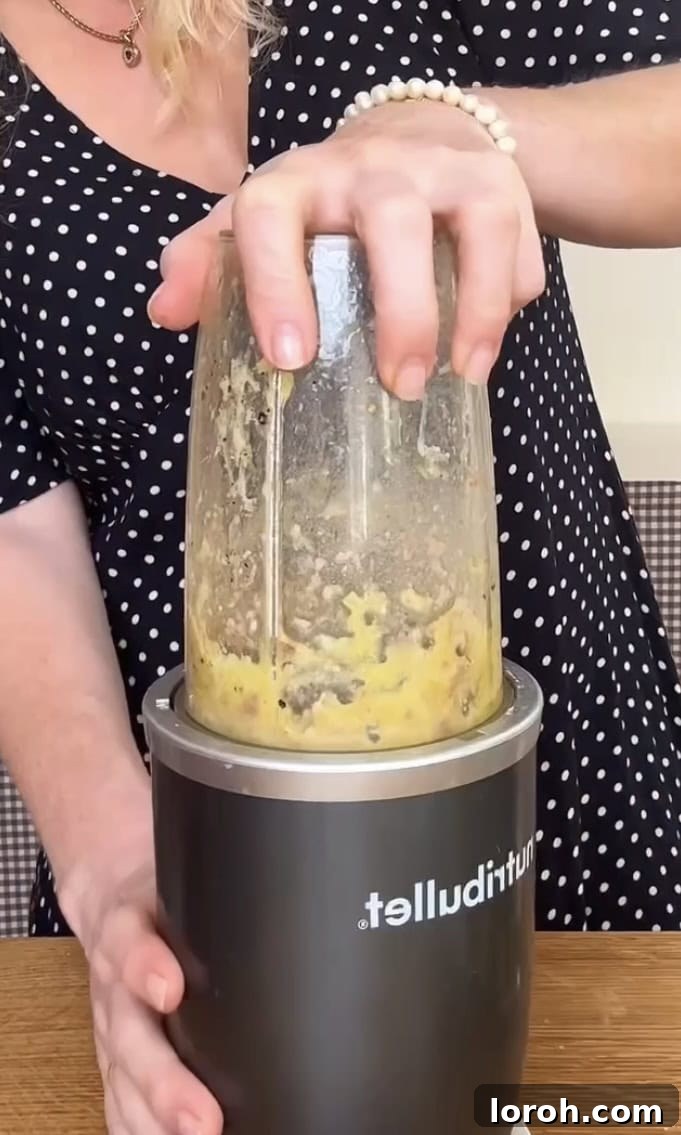Anchovies being blended in a small food processor with oil and seasonings.