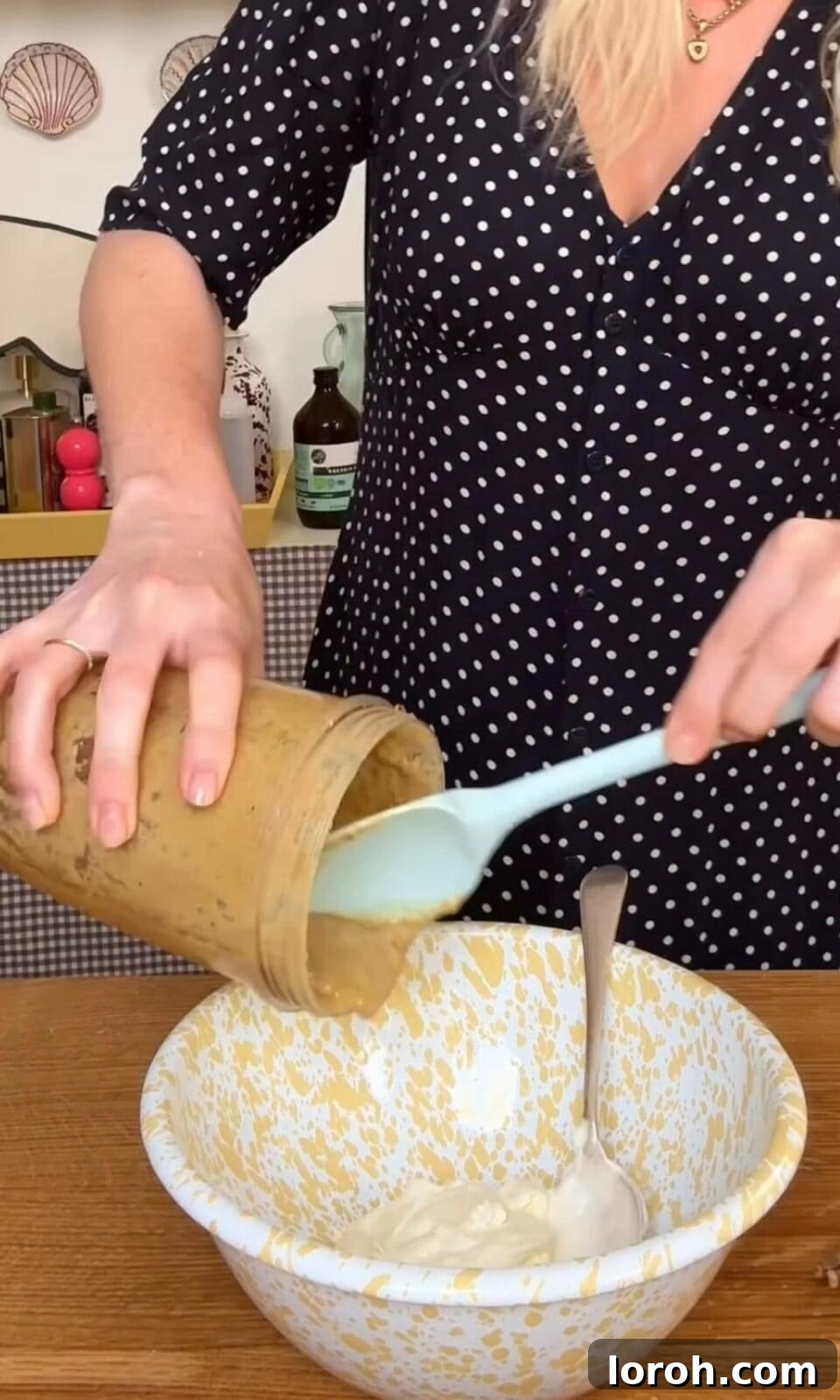 Anchovy paste being gently folded into crème fraîche in a bowl.