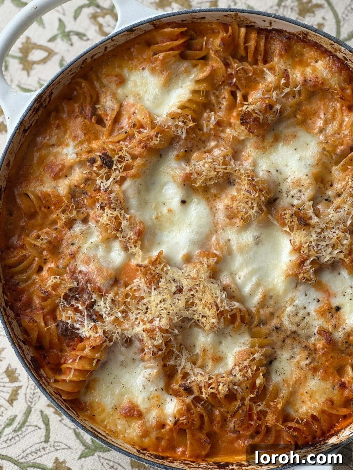 Hearty Bolognese Casserole 3 Close-up shot of the rich and bubbly Bolognese pasta bake in a white baking dish, showing the cheesy top layer.