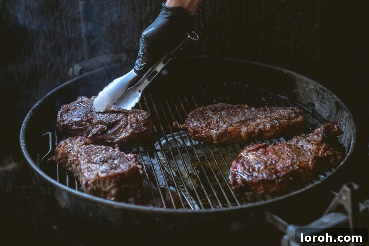sirloin steak being grilled over an open flame, with visible char marks.