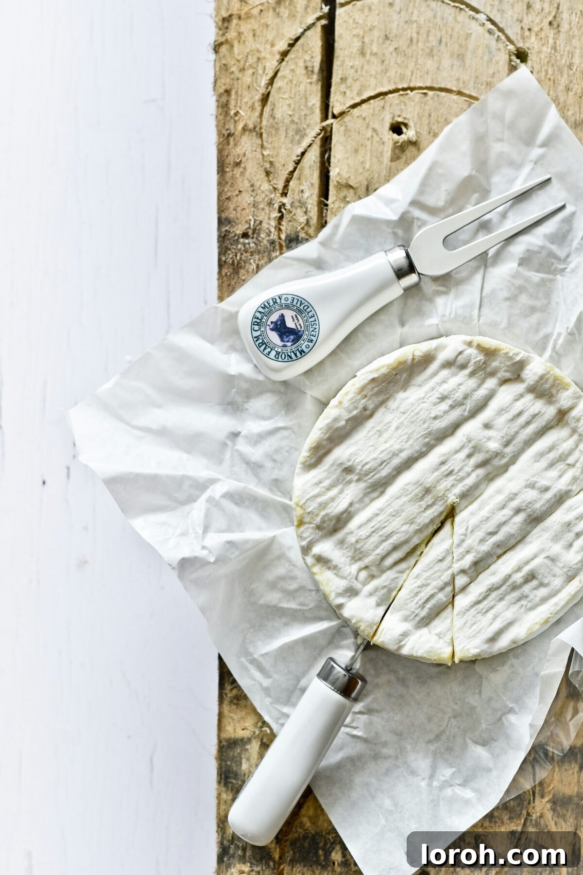 Camembert cheese with a cheese knife, ready to be served on a rustic wooden board.