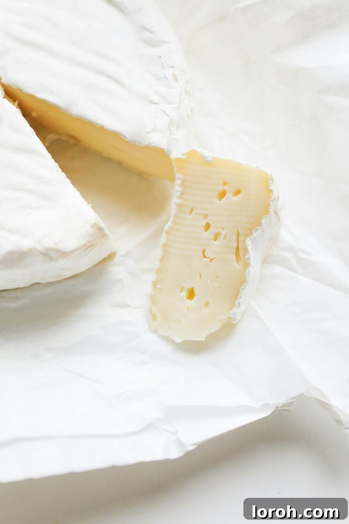 A close-up view of sliced Camembert cheese, beautifully displaying its creamy, soft texture and white rind.