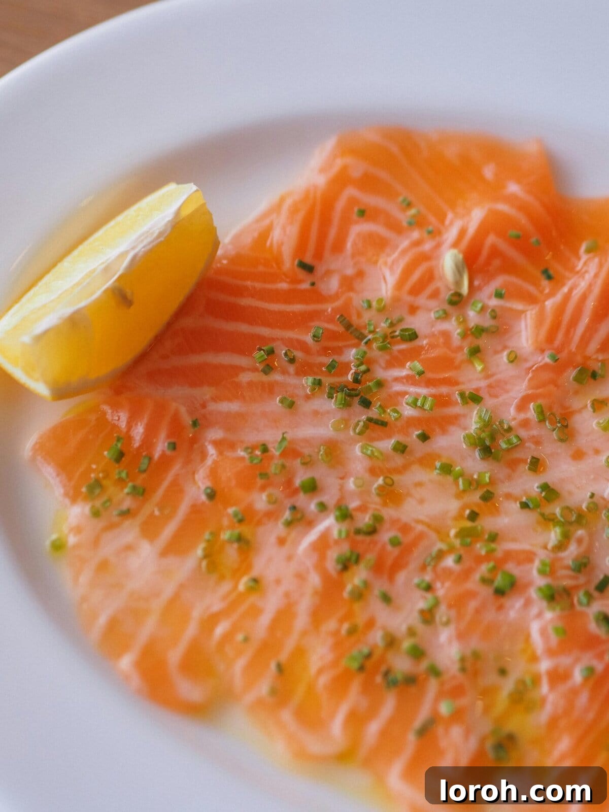 Beautifully arranged salmon carpaccio garnished with fresh lemon slices and capers.