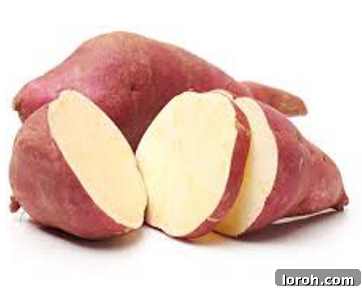 Sliced raw boniato, showcasing its reddish skin and white flesh.
