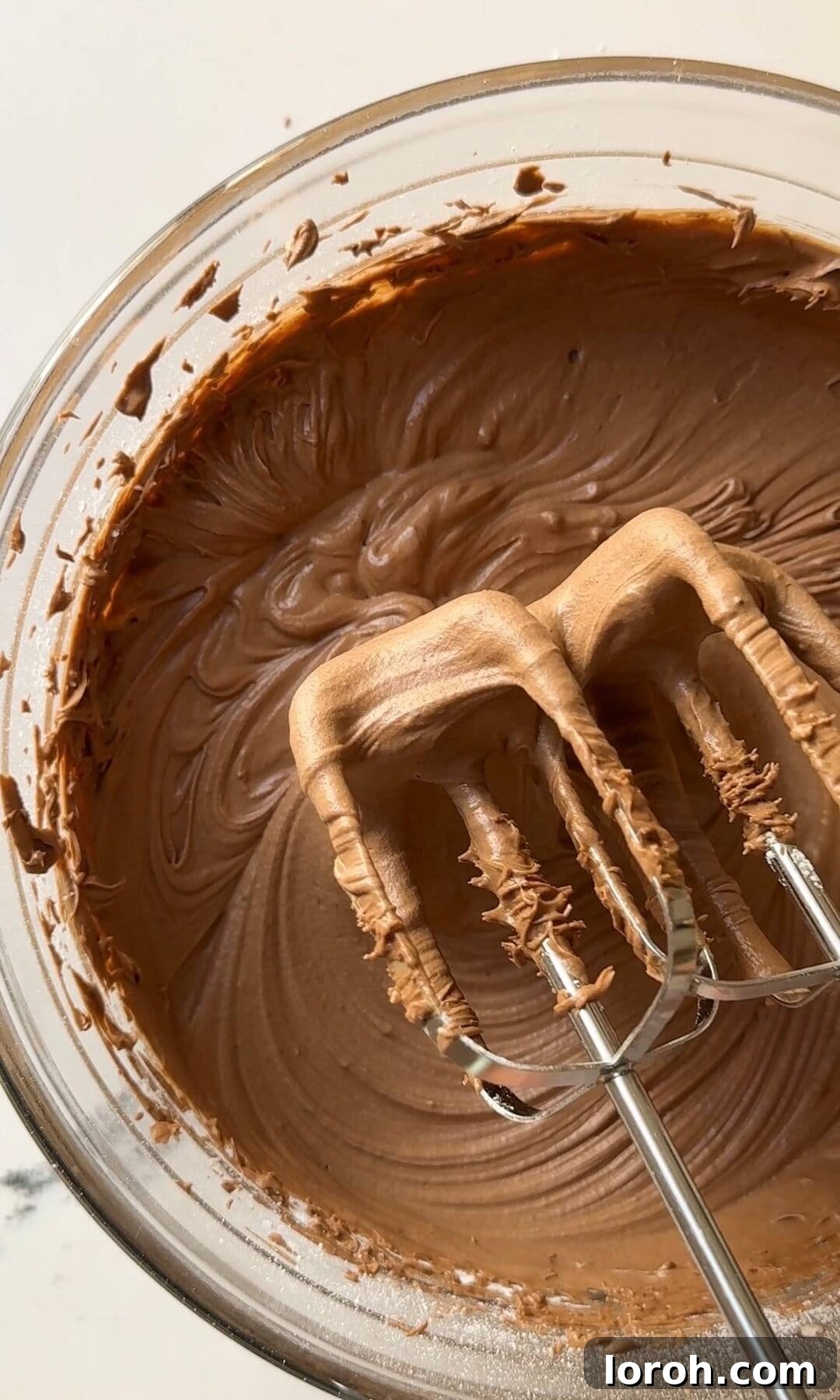 Decadent Chocolate Fudge Cake 12 Whipping the chocolate fudge icing on medium speed until it becomes smooth, thick, and creamy, ideal for frosting.