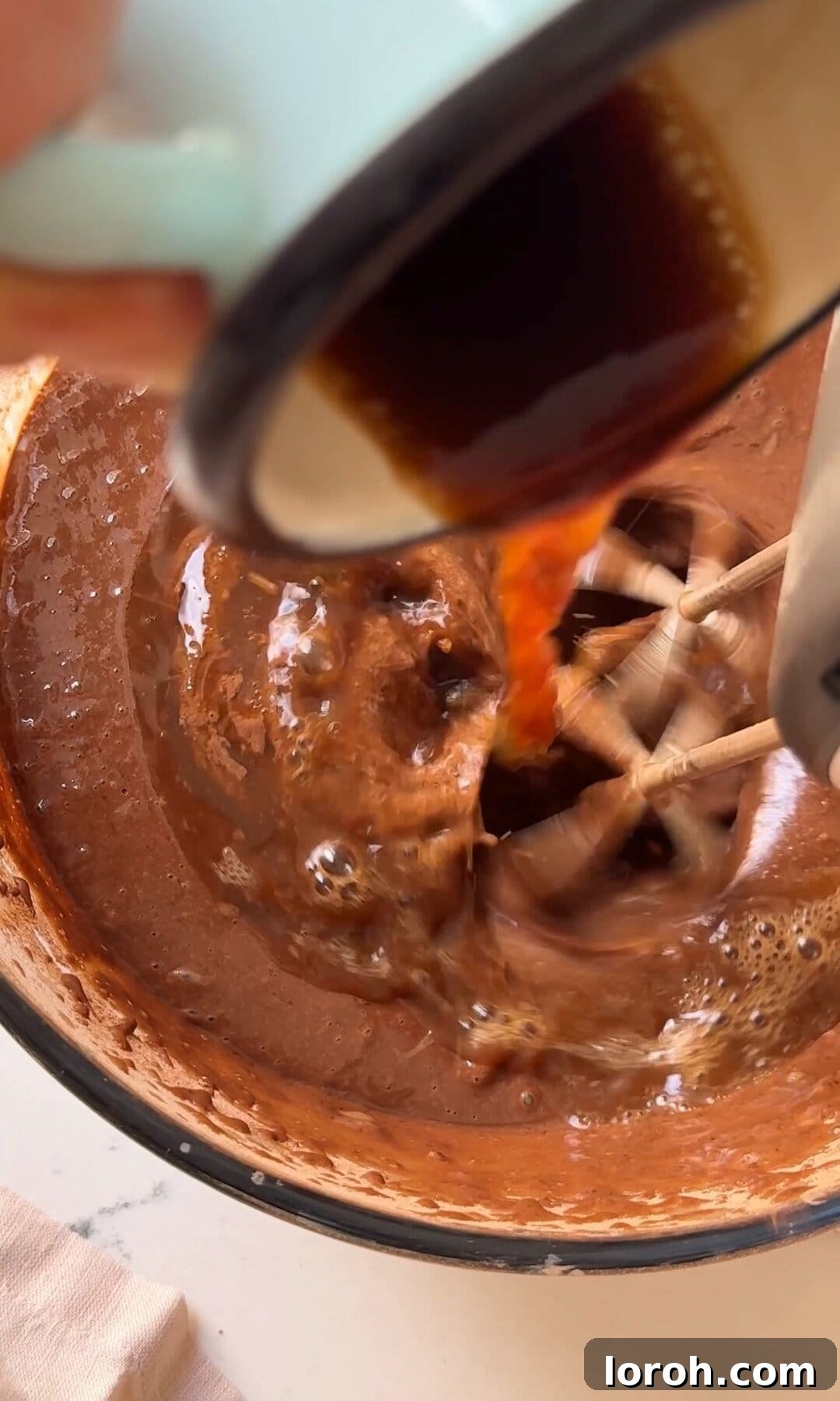 Decadent Chocolate Fudge Cake 7 Pouring hot black coffee into the thick chocolate cake batter, ready for final mixing.