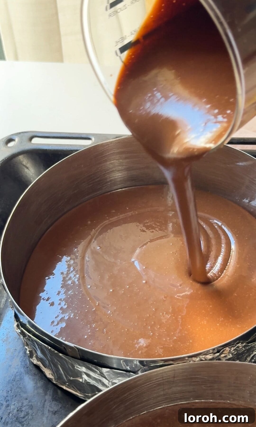 Decadent Chocolate Fudge Cake 8 Dividing the smooth chocolate fudge cake batter evenly into two prepared 8-inch cake tins.