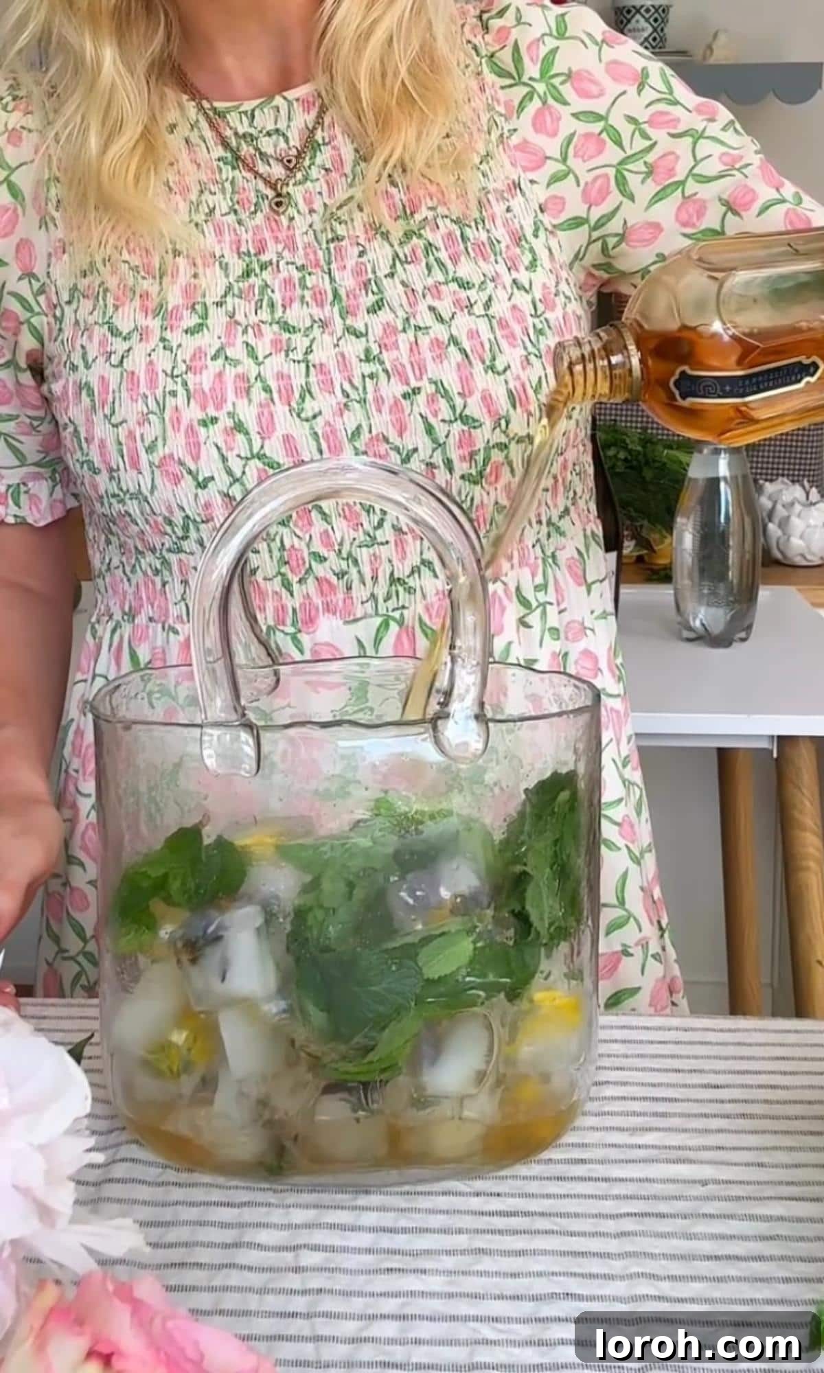 Pouring elderflower liqueur into a glass with ice and mint for a Hugo Spritz.
