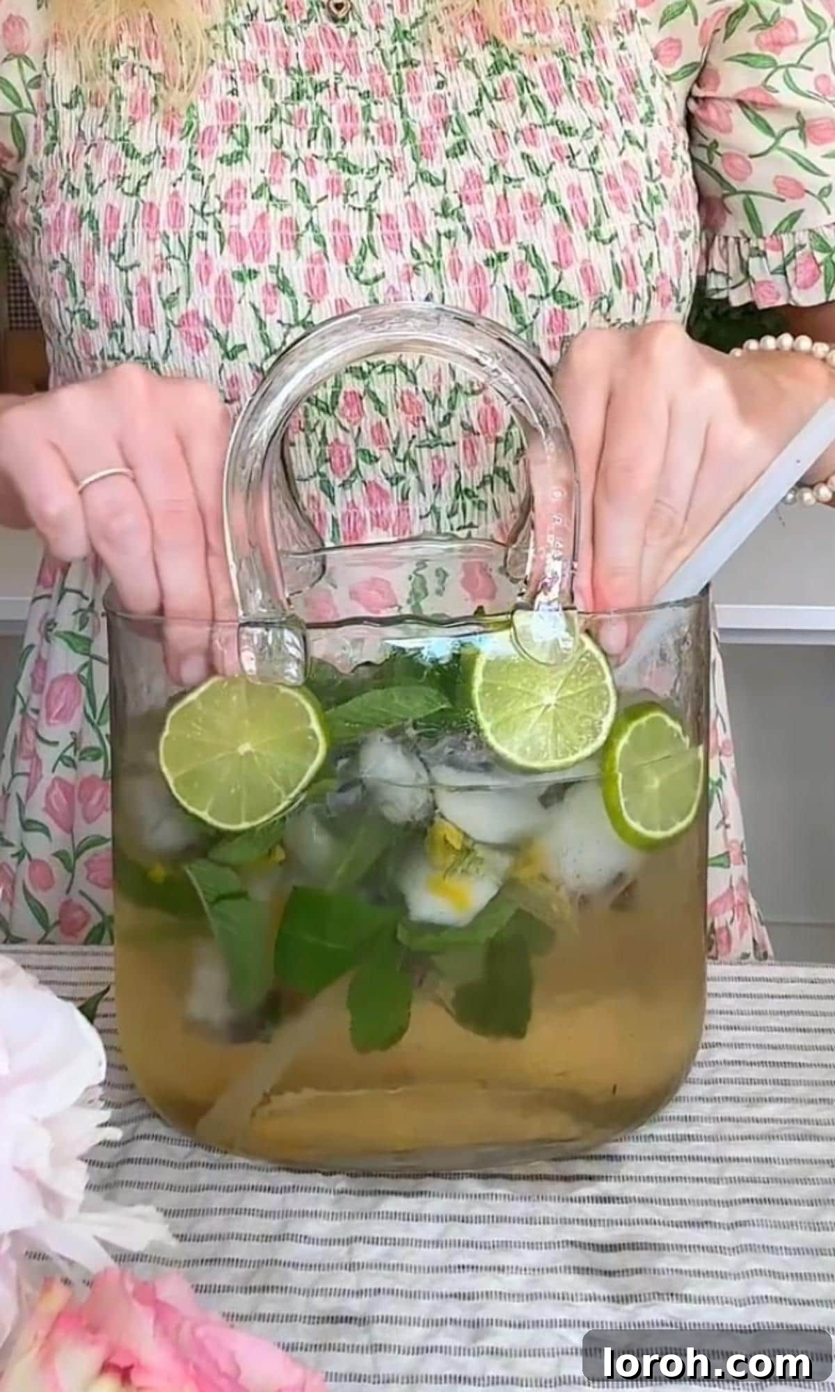 Garnishing a Hugo Spritz with fresh lime slices and a sprig of mint.
