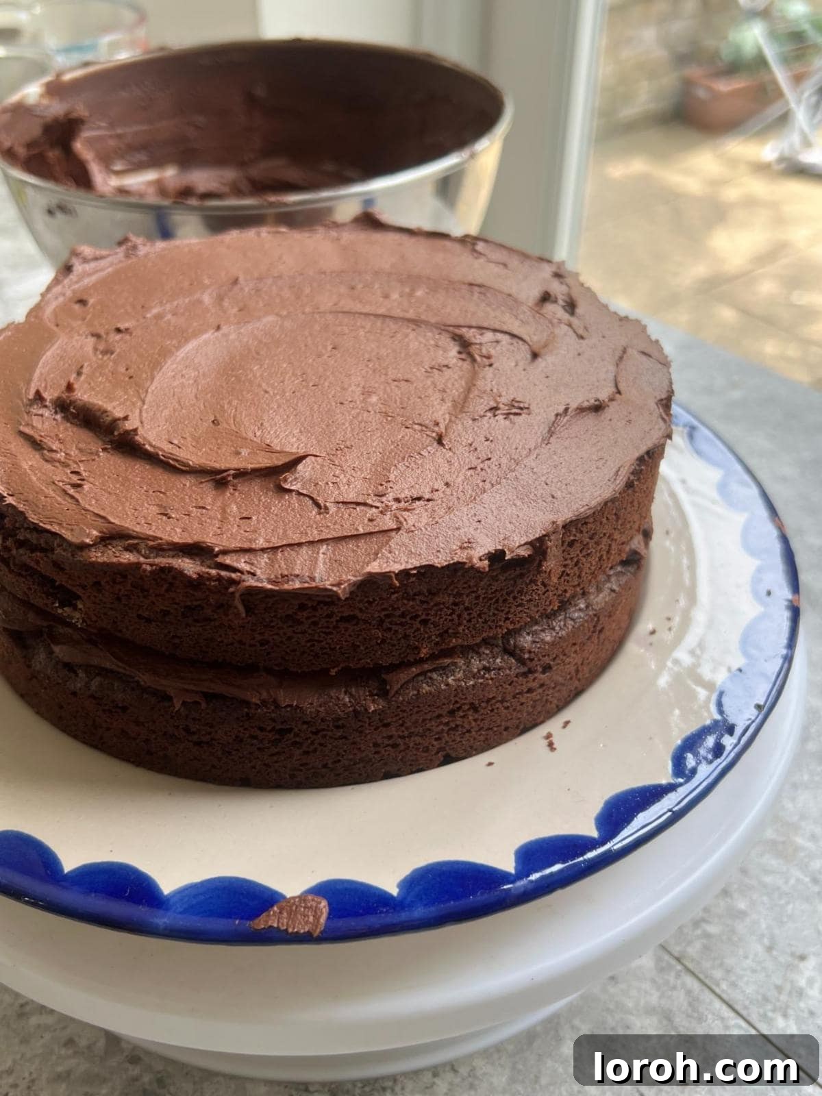 Spreading a thick layer of chocolate ganache over a cake sponge.