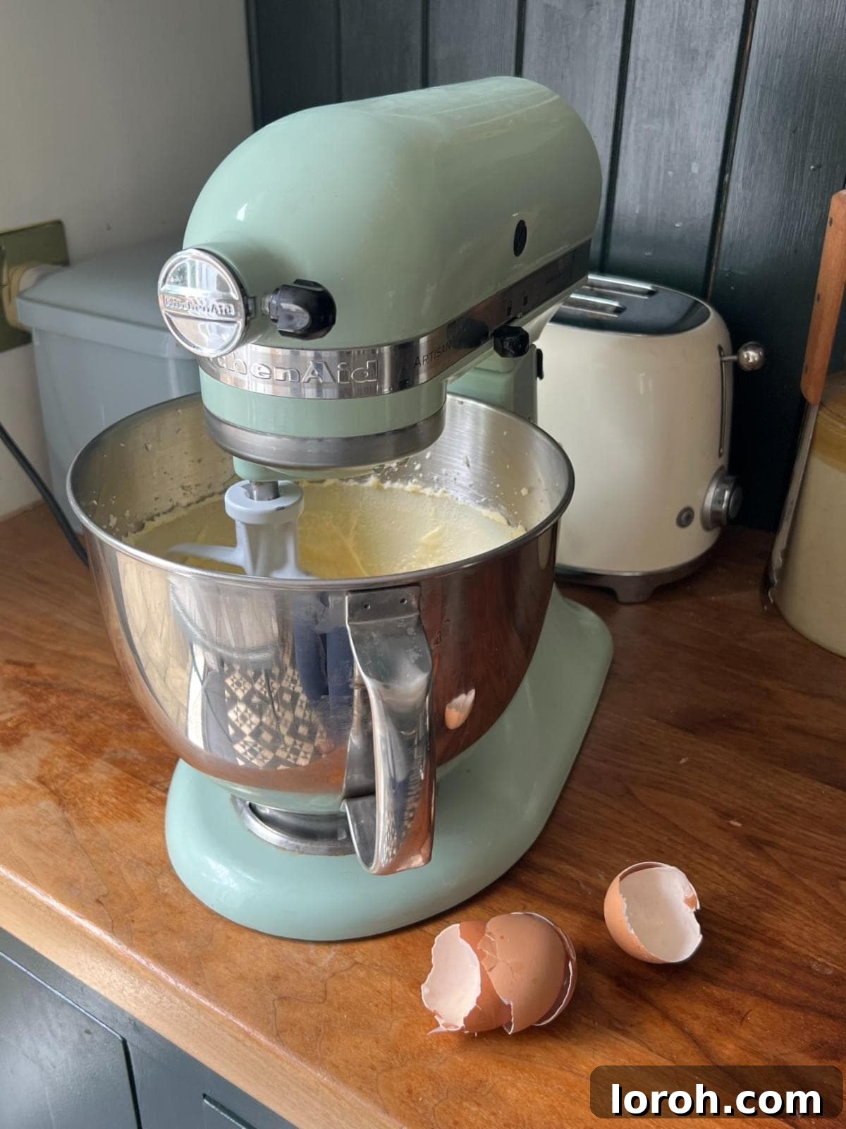 Adding eggs to the butter and sugar mixture in a stand mixer, then incorporating melted chocolate and oil.