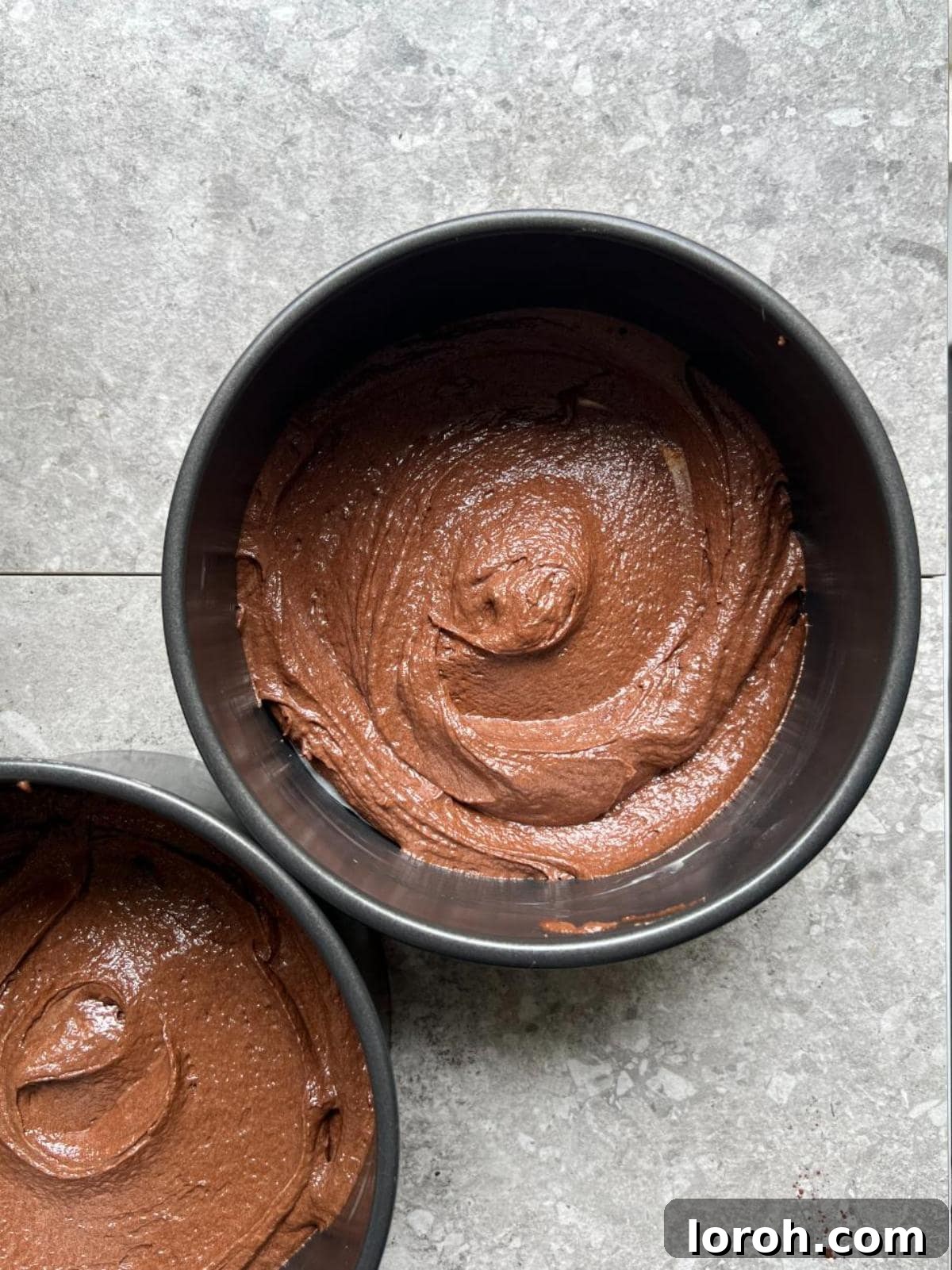 Dividing thin cake batter into three prepared cake tins.
