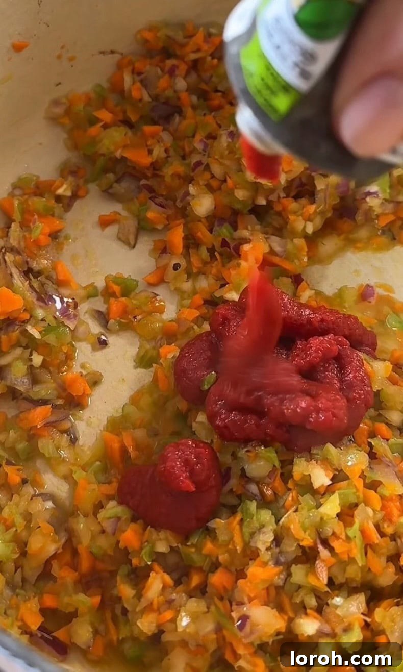 Stirring tomato paste into the softened soffritto vegetables.