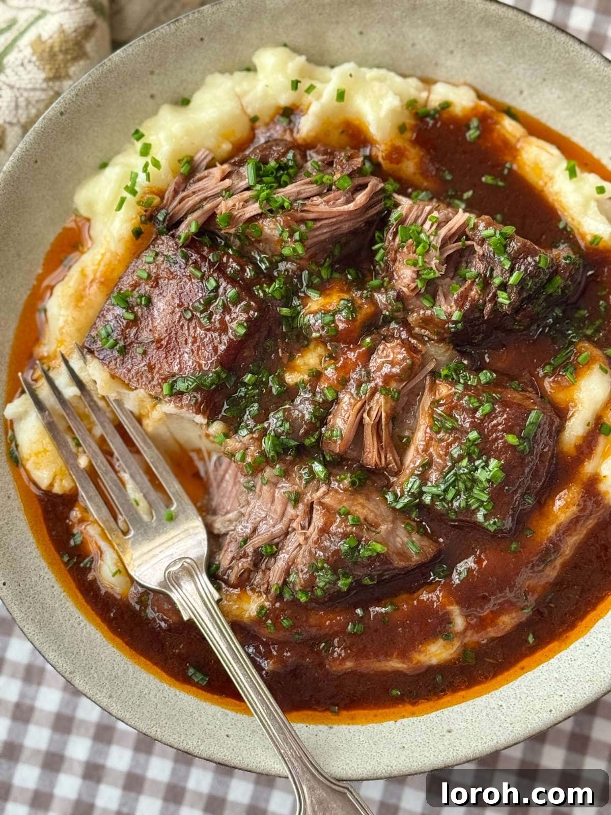 Close-up of beautifully braised beef short ribs on a bed of creamy mashed potatoes, ready to be served.