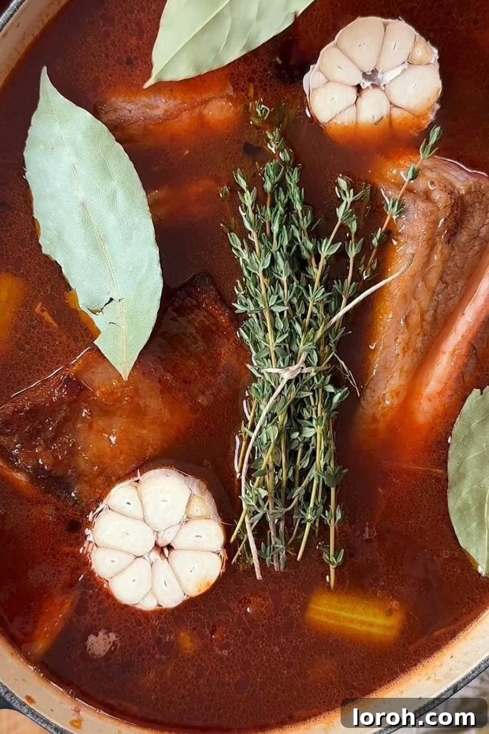A large pot of red wine braised beef short ribs freshly taken out of the oven, bubbling gently.