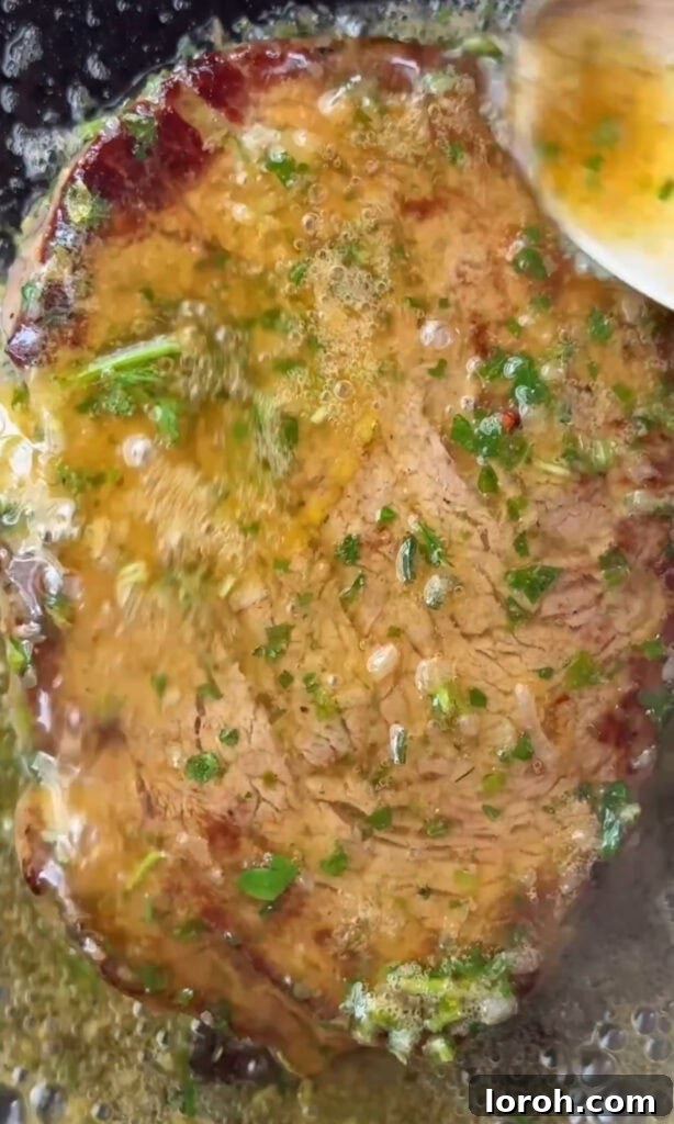 Fast Cowboy Butter Fix 4 Sizzling steak cooking in a pan with generous dollops of cowboy butter melting over it, creating a rich sauce.