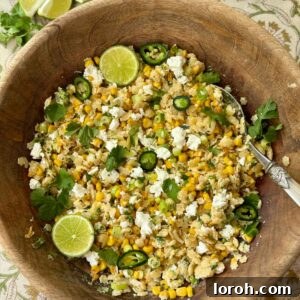 Pastina salad in a wooden bowl with lime slices and feta.
