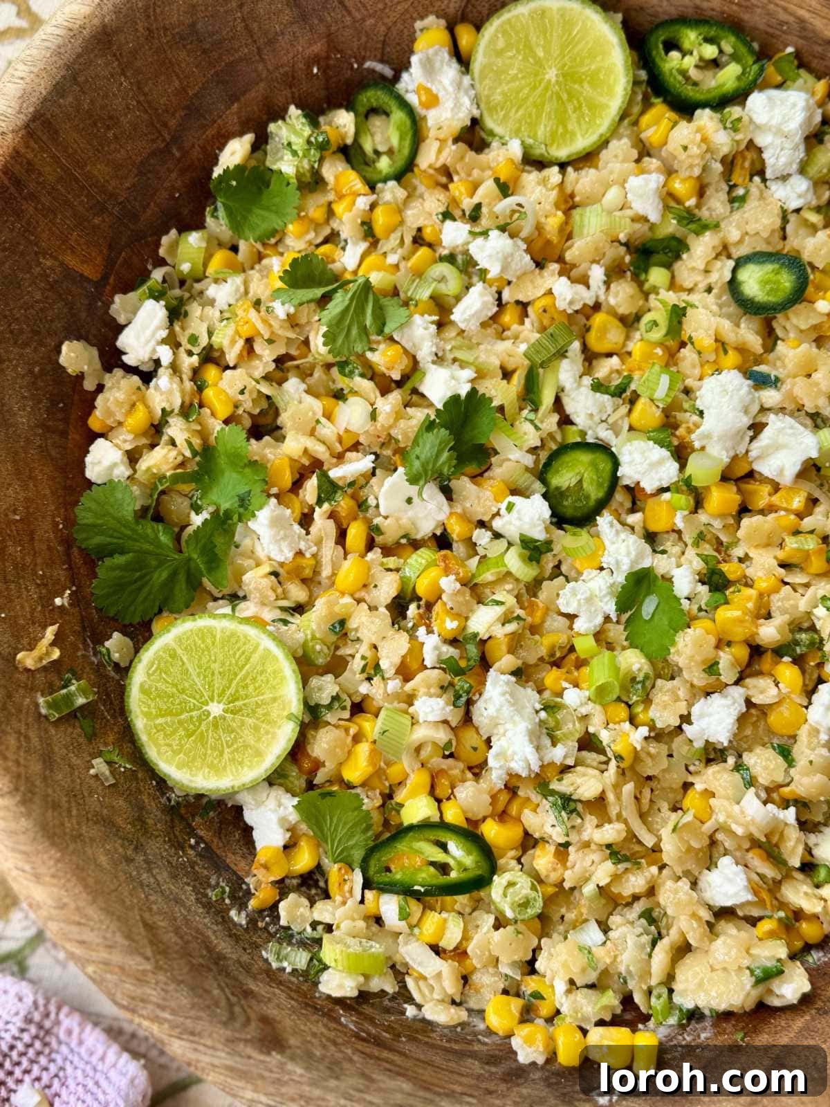 Vibrant Pastina Salad with Smoky Corn and Tangy Feta 3 pastina salad in a wooden bowl with lime slices and feta, garnished for serving.