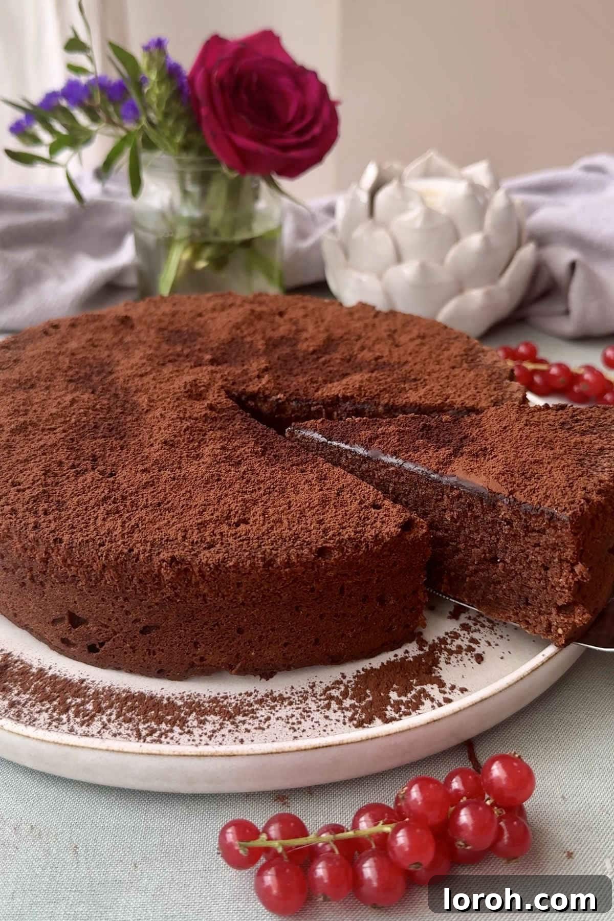 A whole Torta Caprese cake, dusted with cocoa powder, inviting a slice.