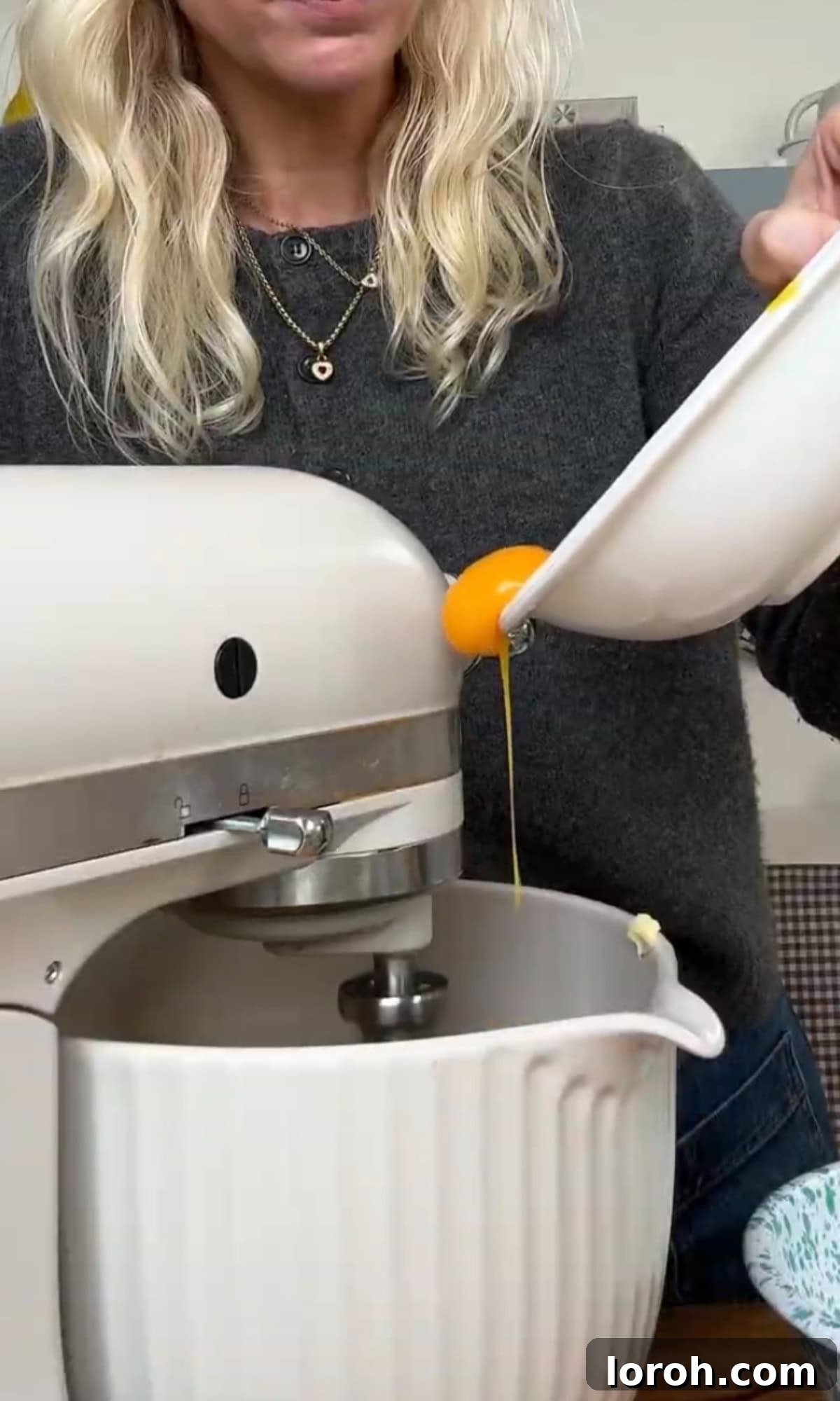 Adding egg yolks one by one to the creamed butter and sugar mixture.